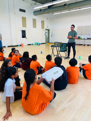 Students hold aficio22 gift boxes, examining the branding and packaging. Our founder, Kaveh, speaks to the students about the importance of branding and packaging in product development during our visit to A Step Beyond.