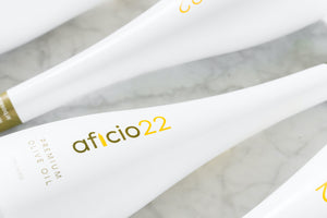 White aficio olive oil bottles on a white marble countertop